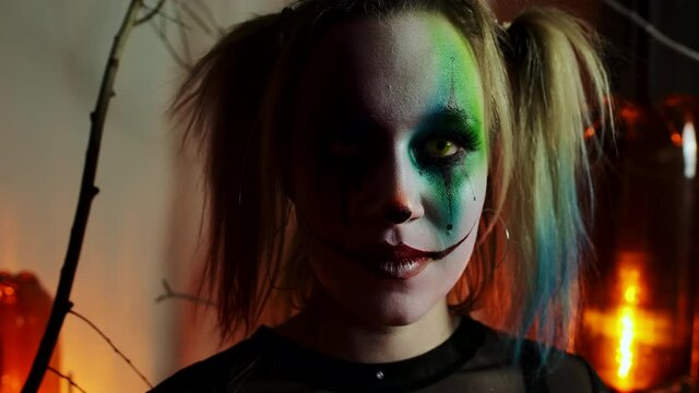 woman in makeup crazy clown posing for camera on Halloween close-up slow motion