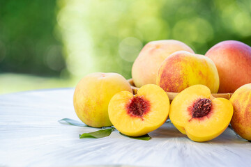 Yellow Peach with sliced on the wooden table over blurred greenery background, Fresh peach on wooden plate in wooden Background.