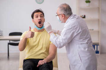 Obraz premium Young male patient visiting old male doctor otorhinolaryngologis