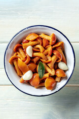 Pickled mushrooms with garlic and a bay leaf, shot from above on a rustic wooden background