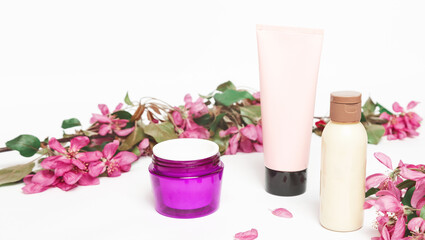Obraz na płótnie Canvas tube of floral moisturizing face tonic and jar of hand cream with apple flowers isolated on white background. natural organic cosmetic product