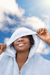 Young preteenage girl playing with her hoodie, sunny day, blue sky, white clouds