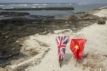 Couple on beach running with UK and Vietnam flags