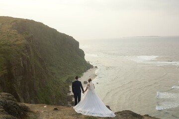 bride and groom on cliff overlooking sea and horizon - Powered by Adobe