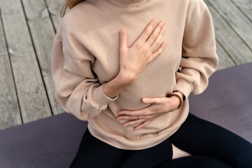 Close-up of a woman's hands on her chest while doing breathing exercises