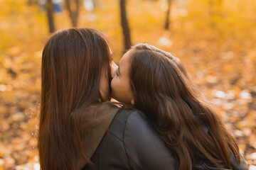 Mother and daughter spend time together in autumn yellow park. Season and single parent concept.