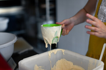 Baker measures sourdough for bread with a mug
