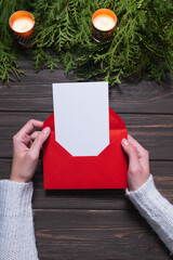 Woman's hands holding letter with blank card on wooden background. Chritsmas design.