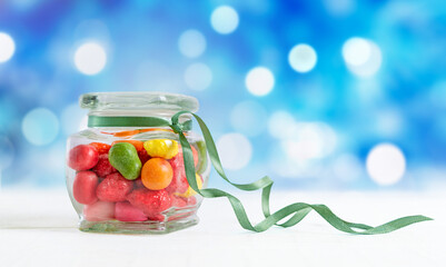 Colorful candies in a jar on a blue bokeh background. Holiday sweet treats.