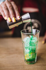 Making a green cocktail in a glass glass at a bar - lemon and banana syrup