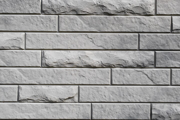 Gray textured brick wall, long and narrow horizontal decorative stone imitation of old, rough and...