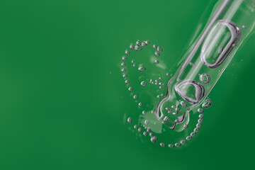 Aloe vera gel cosmetic texture in glass dropper on green bubbles background close-up, Liquid gel or...