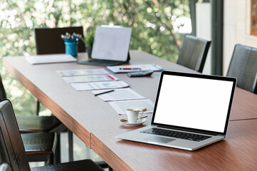 Blank screen laptop computer on wooden table in meeting room.
