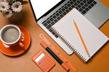 Computer laptop, coffee cup, notebook and calculator on accountant workspace.