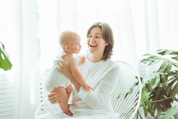 Portrait of happy mother and baby, parent and little kid relaxing at home. Family having fun together