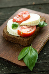Sandwich with cheese, tomatoes and basil on a rustic wooden board. Healthy food. Food background
