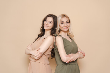 Blonde mother and brunette adult daughter wearing identical clothes, different colors, posing over...
