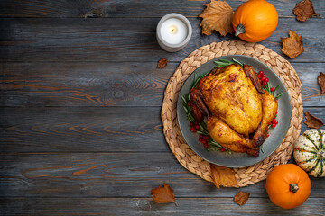 Baked chicken for Thanksgiving Day. Roasted chicken or turkey with herb and pumpkins for thanksgiving dinner on wooden table. Festive table settings for Thanksgiving Day. Copy space