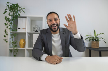 African american man in video call waves hand saying hello to coworker. Latino CEO looking at camera in business meeting © Daniel