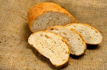 Bread, cut into slices, against the background of fabric.