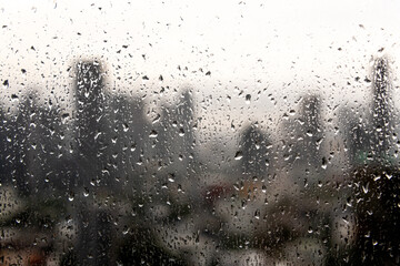 Rain droplets on a window with the Bangkok city skyline in the background