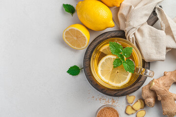A cup of tea with lemon, ginger and mint on a gray background. A healthy, warming drink.