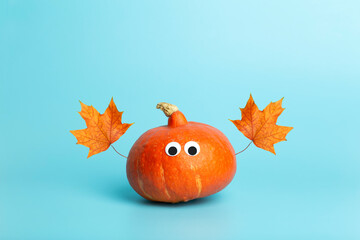 Pumpkin for halloween and thanksgiving on empty blue minimal background. Funny autumn pumpkin with eyes for children. Cheerful and funny vegetables concept.
