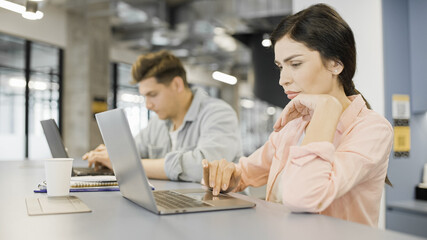 Company colleagues typing emails on laptops, programming in coworking space
