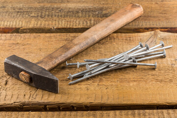 Vintage hammer with nails on wood background