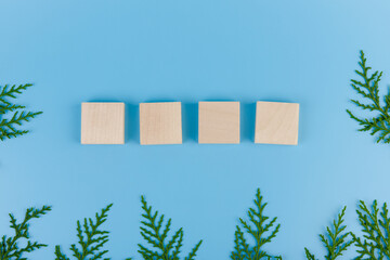 Four Wooden blocks whith cypress branches on a blue background. The concept of the New year, Christmas.