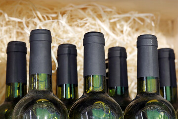 Dusty wine bottles in a wood shavings. Liquor store, red wine in box for transportation