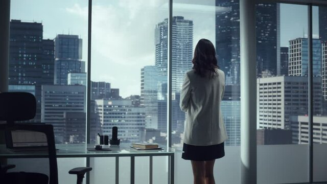 Ambitious Successful Businesswoman Standing in Office Looking out of Window on Big City. Confident High Achievement Female Digital Entrepreneur Thinking of Investment Strategy for e-Commerce Software