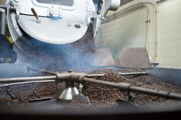 Close-up of coffee roasting machine at work. Interior of coffee production workshop with set up roasting equipment. Production, industry, manufacturing process concept