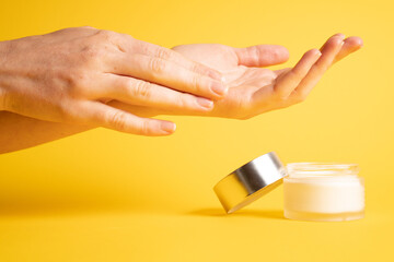 Hand cream on yellow. Applying hand moisturizer cream on female hands