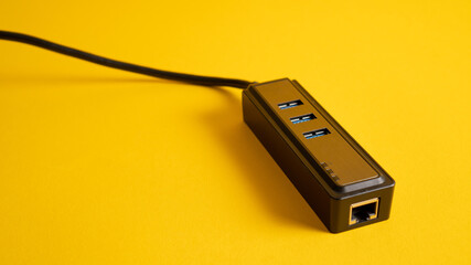 Close up black USB hub isolated on yellow. Three ports USB charger