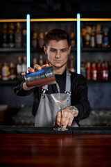 barman is making cocktail with steel shaker