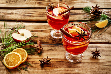 Wine glasses of hot mulled wine with spices, apple and orange on wooden table. Christmas...