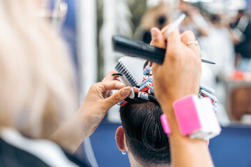 Hairdresser fixing a costumer's hair with rollers to dye it