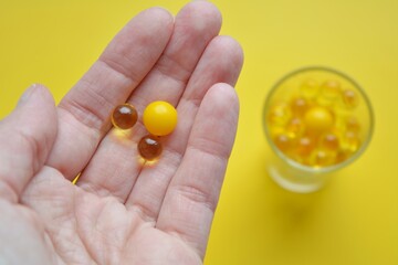 pills vitamins in hand yellow background