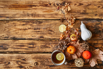 Autumn flat lay. Cup of lemon hot tea and star anise, pumpkin and another colorful fall fruits and dried leaves on wooden background top view. Cozy fall mood. Space for text. Thanksgiving.