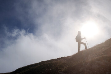 Young woman hiker with a backpack on the top of the mountain