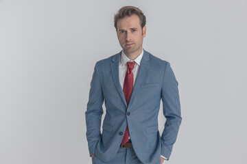 handsome unshaved businessman posing with hands in pockets