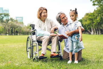 Portrait of happy love asian grandfather with grandmother and asian little cute girl enjoy relax in summer park.Young girl with their laughing grandparents smiling together.Family and togetherness