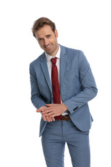 smiling young businessman in blue suit being happy and rubbing palms