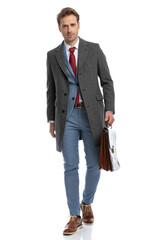 happy businessman with jacket holding briefcase and walking