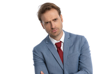attractive young businessman in blue suit crossing arms and frowning