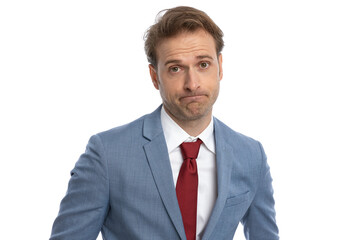 elegant young guy in blue suit making a disappointed face and posing