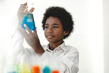 African american cute little boy student child learning research and doing a chemical experiment while making analyzing and mixing liquid in glass at science class on the table.Education