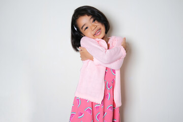 Asian little girl hugging her self and showing happy face expression