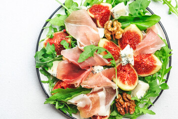 Sweet fig salad with jamon, blue cheese, walnuts, arugula on white background, top view, copy space